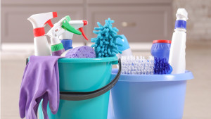 two cleaning buckets filled with scrub brushes and spray bottles and rubber gloves draped over a side.