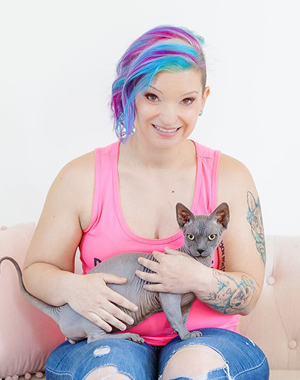 Laura Cassiday sitting on a white couch with gray cat in her lap